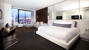 Una camera d'albergo moderna con un letto grande, una scrivania, una sedia e vista sulla città.
