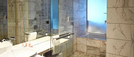 Een moderne badkamer met een douche in glazen cabine, een grote spiegel en een marmeren vloer.