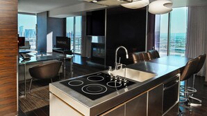 A modern kitchen with a central island, a built-in stove, and a large window offering a city view.