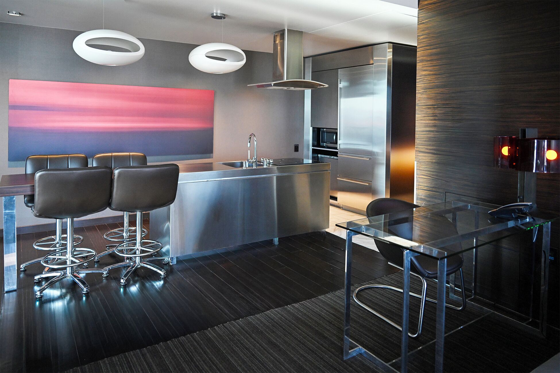 A modern kitchen with a central island, bar stools, and pendant lighting.