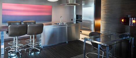 A modern kitchen with a central island, bar stools, and pendant lighting.
