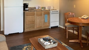 Una cocina compacta con armarios de madera, un refrigerador, estufa, microondas y un comedor con mesa y sillas.