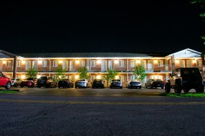 A motel with multiple rooms, a parking lot, and a small vehicle parked outside. - Affordable Corporate Suites Christiansburg (Christiansburg)