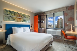 A modern hotel room with a large bed, a desk, a chair, and a window with a city view. - Hotel Le Jolie (Brooklyn)