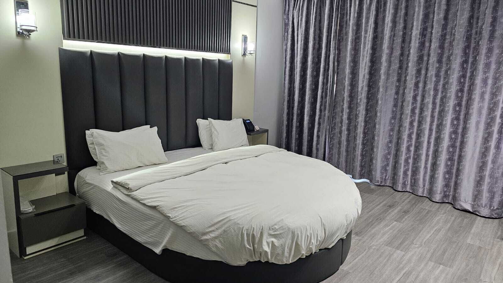 Ein modernes Hotelzimmer mit einem großen Bett, einem Nachttisch und einem Beistelltisch.