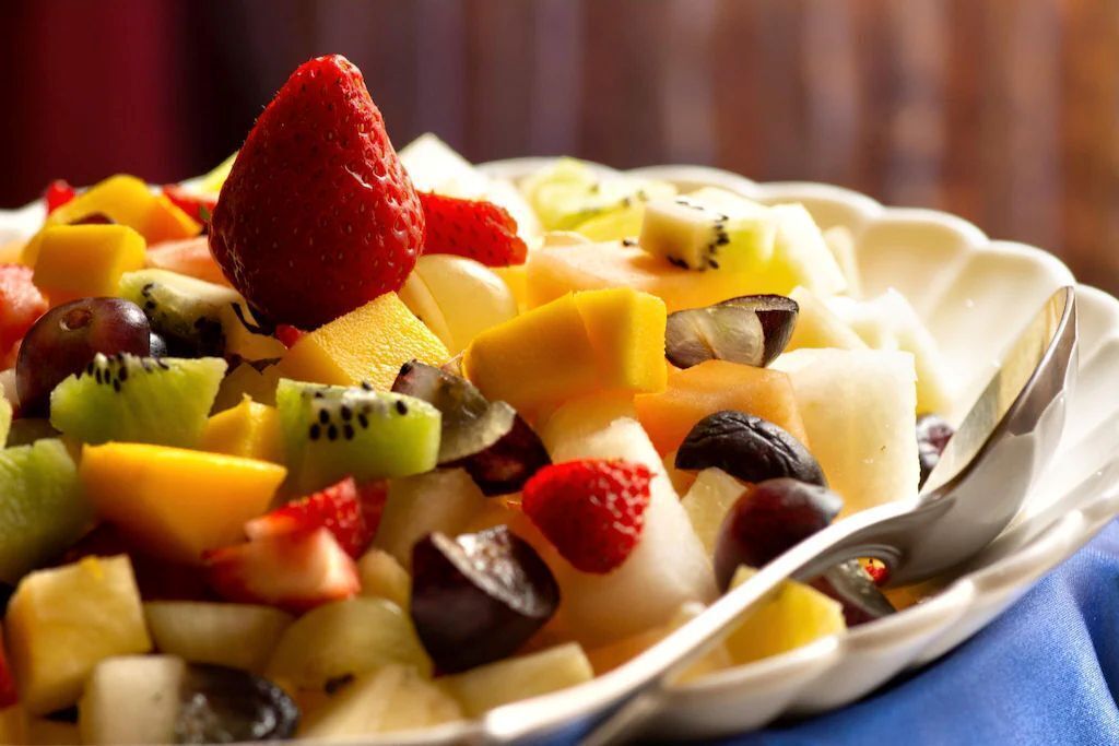 A fruit salad with a variety of fruits including strawberries, kiwi, mango, and grapes.