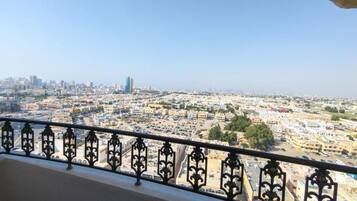 A cityscape with a view of buildings and a parking lot from a balcony with ornate railings.