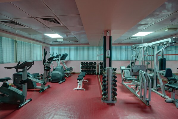 Un gimnasio con diverso equipamiento de ejercicio, incluyendo cintas de correr, mancuernas y máquinas de pesas.