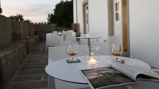 A table with two glasses of wine, a candle, and a magazine. - Montebelo Palácio dos Melos Viseu Historic Hotel (Viseu)