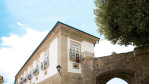 A historic building with a stone archway, white walls, and a tiled roof. - Montebelo Palácio dos Melos Viseu Historic Hotel (Viseu)