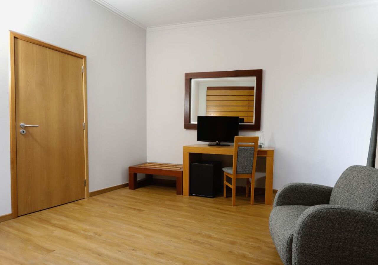 Een kamer met een houten deur, een bureau met een computer, een stoel en een bank.
