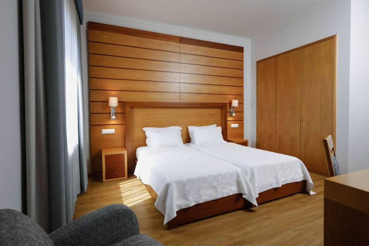 A bedroom with a wooden headboard, a double bed, bedside tables, and a wardrobe.