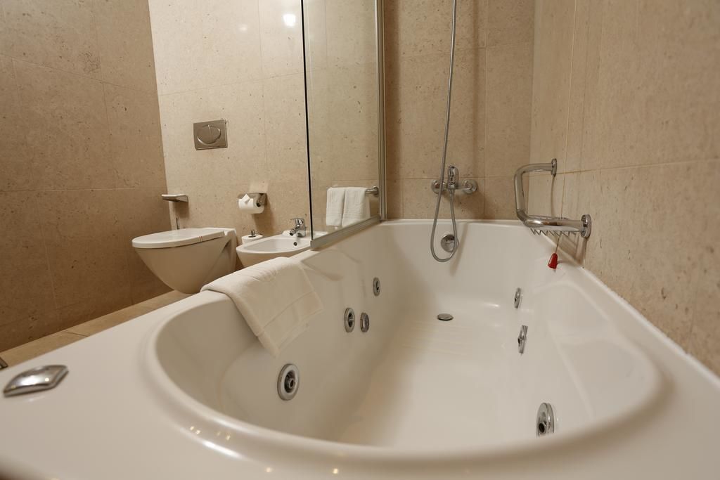 A bathroom with a large bathtub, a toilet, and a sink.