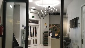 Un moderno vestíbulo de hotel con mostrador de recepción, una araña y una escalera que conduce a los pisos superiores.