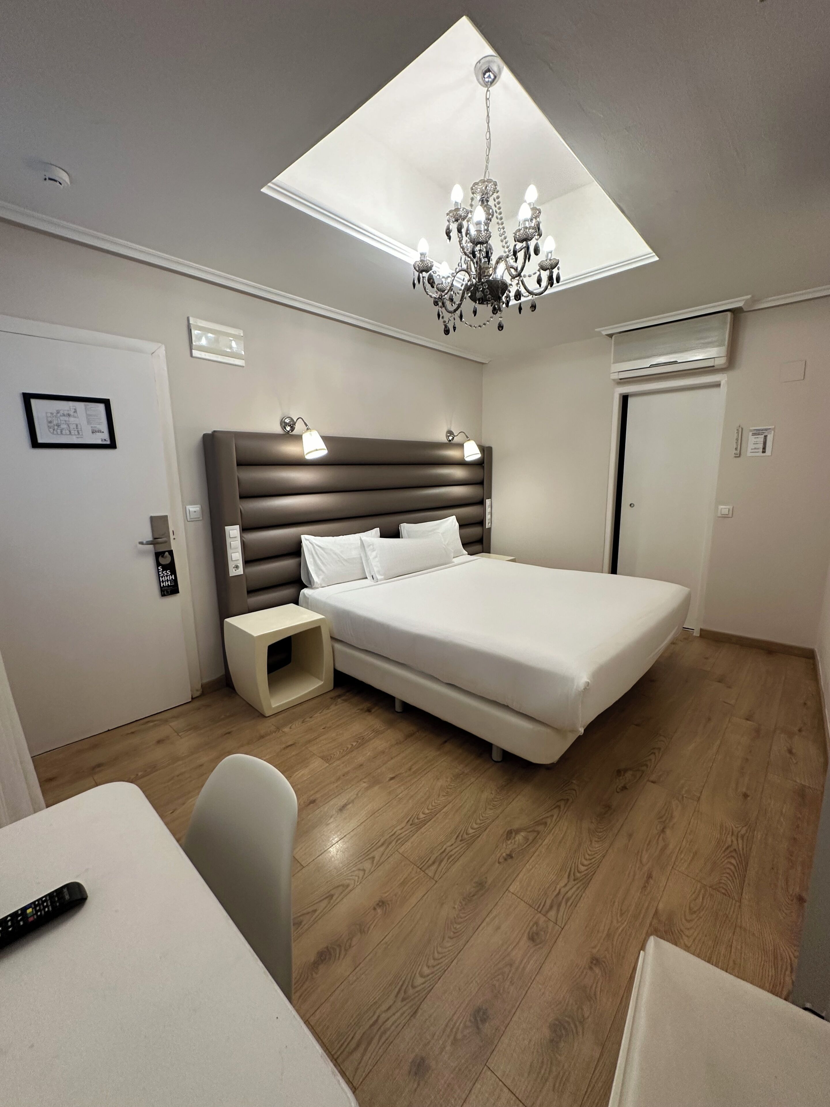 Una camera da letto moderna con un lucernario, un lampadario, un letto, comodini e una scrivania.