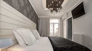 Un dormitorio moderno con una cama grande, una mesita de noche, una araña, un televisor y vistas al exterior.