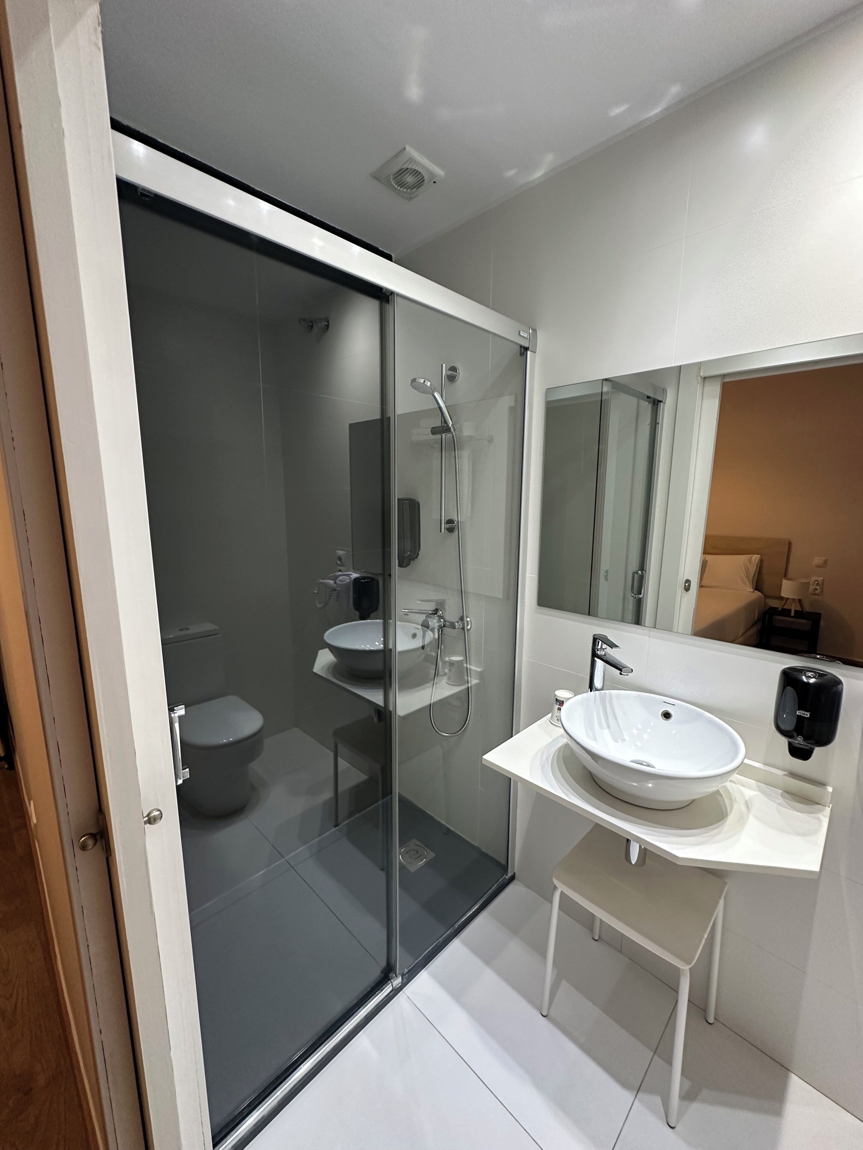Een moderne badkamer met een douchecabine van glas, een wit wastafelmeubel en een grote spiegel.
