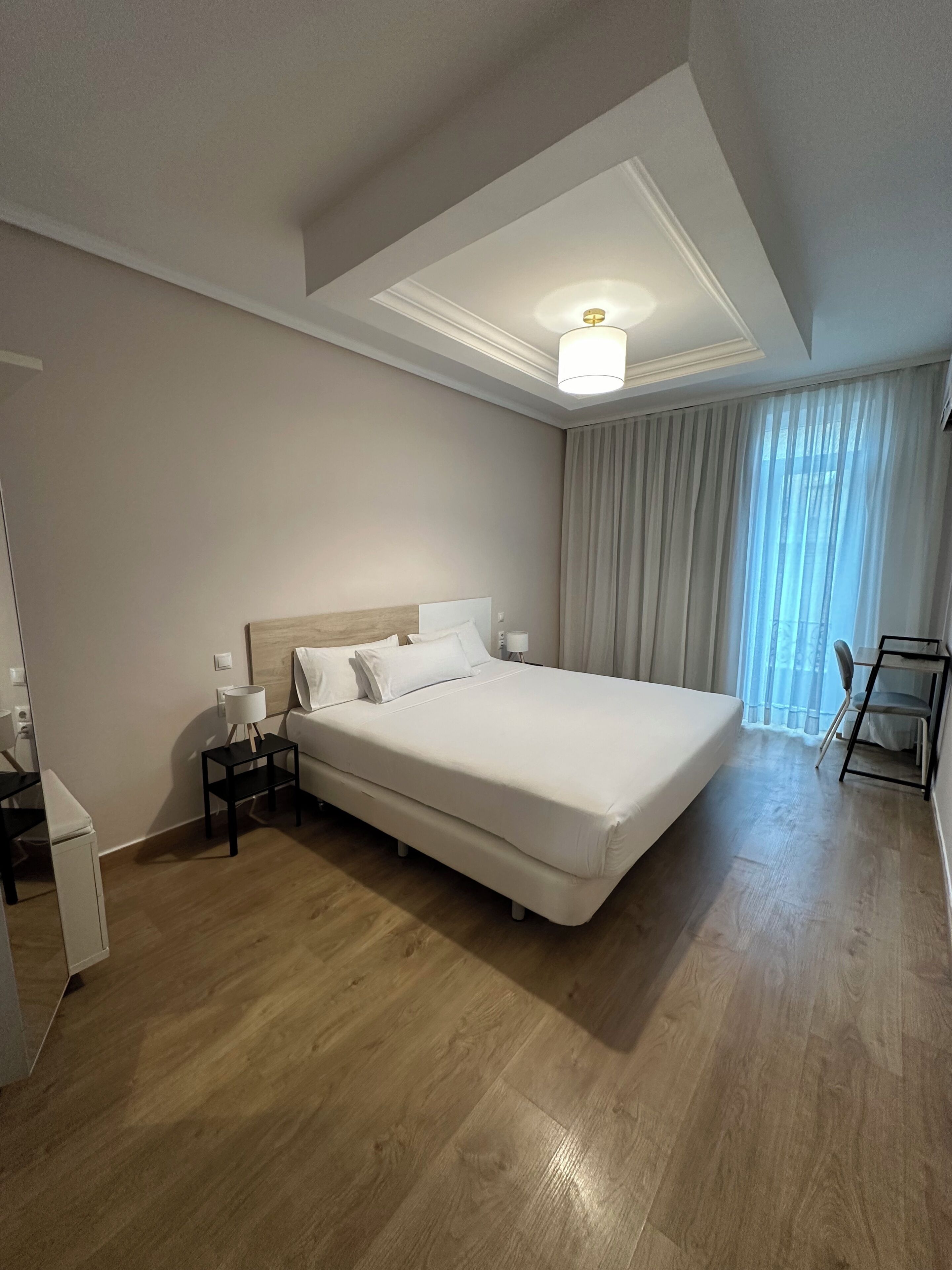 Une chambre d’hôtel avec un grand lit, des tables de chevet, un bureau et une chaise.