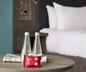 A round wooden table with two glass bottles and a packet of Bronte biscuits.