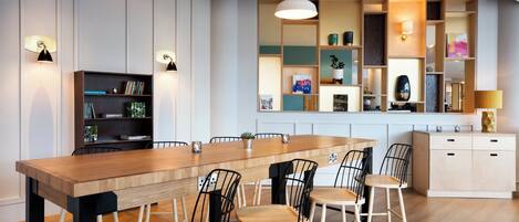 A modern kitchen with a wooden island, black chairs, and pendant lighting.