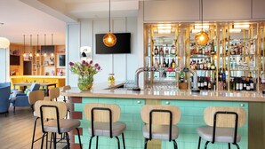 A bar area with a counter, stools, and a television mounted on the wall. - Leonardo Hotel Liverpool (Liverpool)