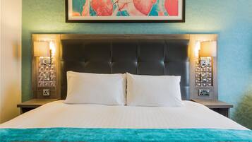 A neatly made bed with a teal throw blanket, a dark headboard, and two bedside lamps.