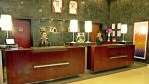A reception desk with two receptionists, a fish bowl, and framed certificates on the wall. - ibis Kuwait Salmiya (Salmiya)