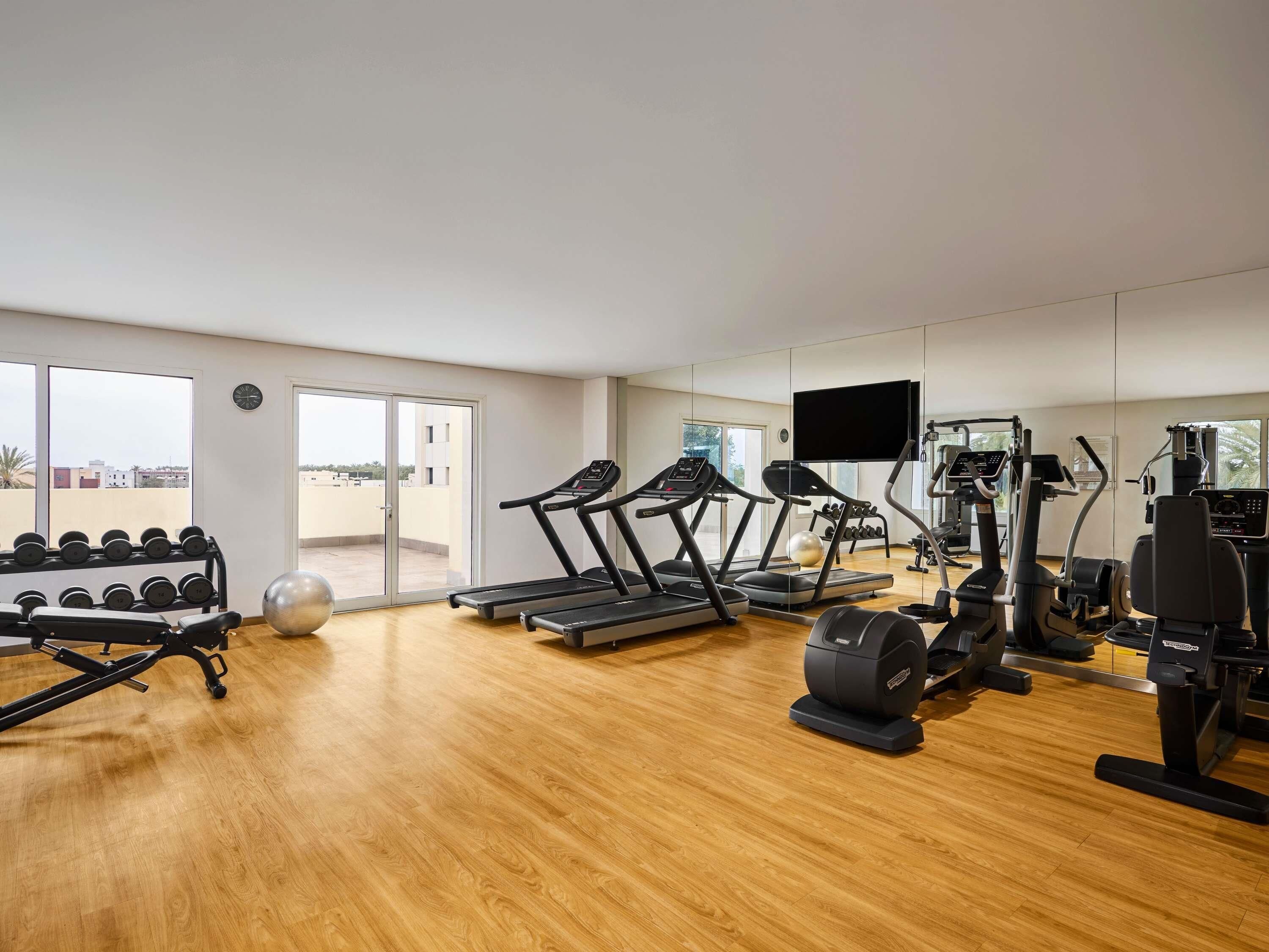 A spacious gym with treadmills, elliptical machines, and free weights.