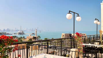 Una terraza con mobiliario exterior, vistas del horizonte urbano y una masa de agua.