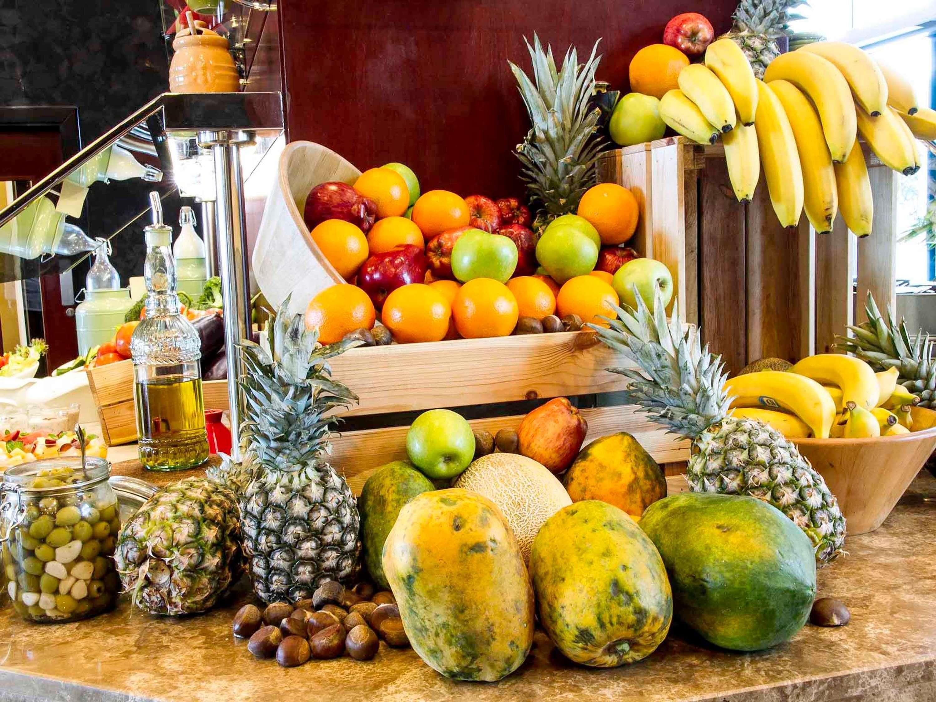 A variety of fruits and a bottle on a counter.