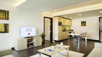 Una sala de estar moderna con un televisor de pantalla plana, una mesa de centro y un comedor, con una cocina visible al fondo.