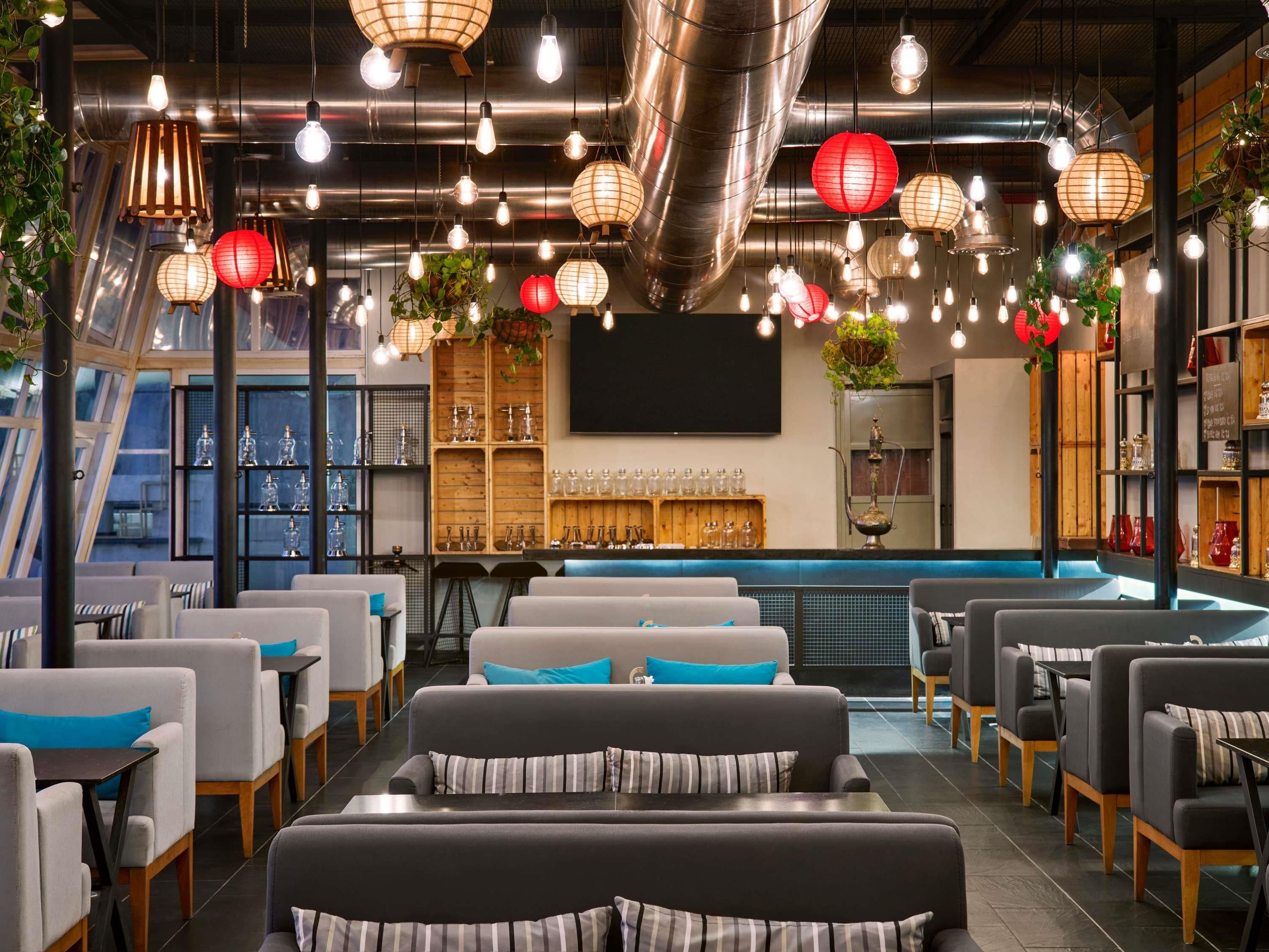 En modern restauranginteriör med sittplatser, hängande lampor och dekorativa element.