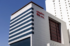 A modern hotel building with a prominent sign reading "ibis HOTEL". - ibis Kuwait Salmiya (Salmiya)