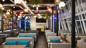 L’intérieur d’un restaurant, avec des tables, des luminaires suspendus et une enseigne indiquant « IL TERRAZZO ».