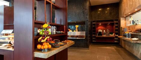 Un hall de hotel con zona de buffet, bar y área de estar con vistas.