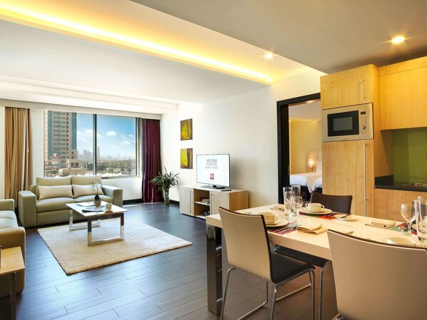 A modern hotel room with a living area, dining space, and kitchenette. - ibis Kuwait Salmiya (Salmiya)