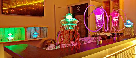 A bar area with neon lights, a television, and a wooden counter.
