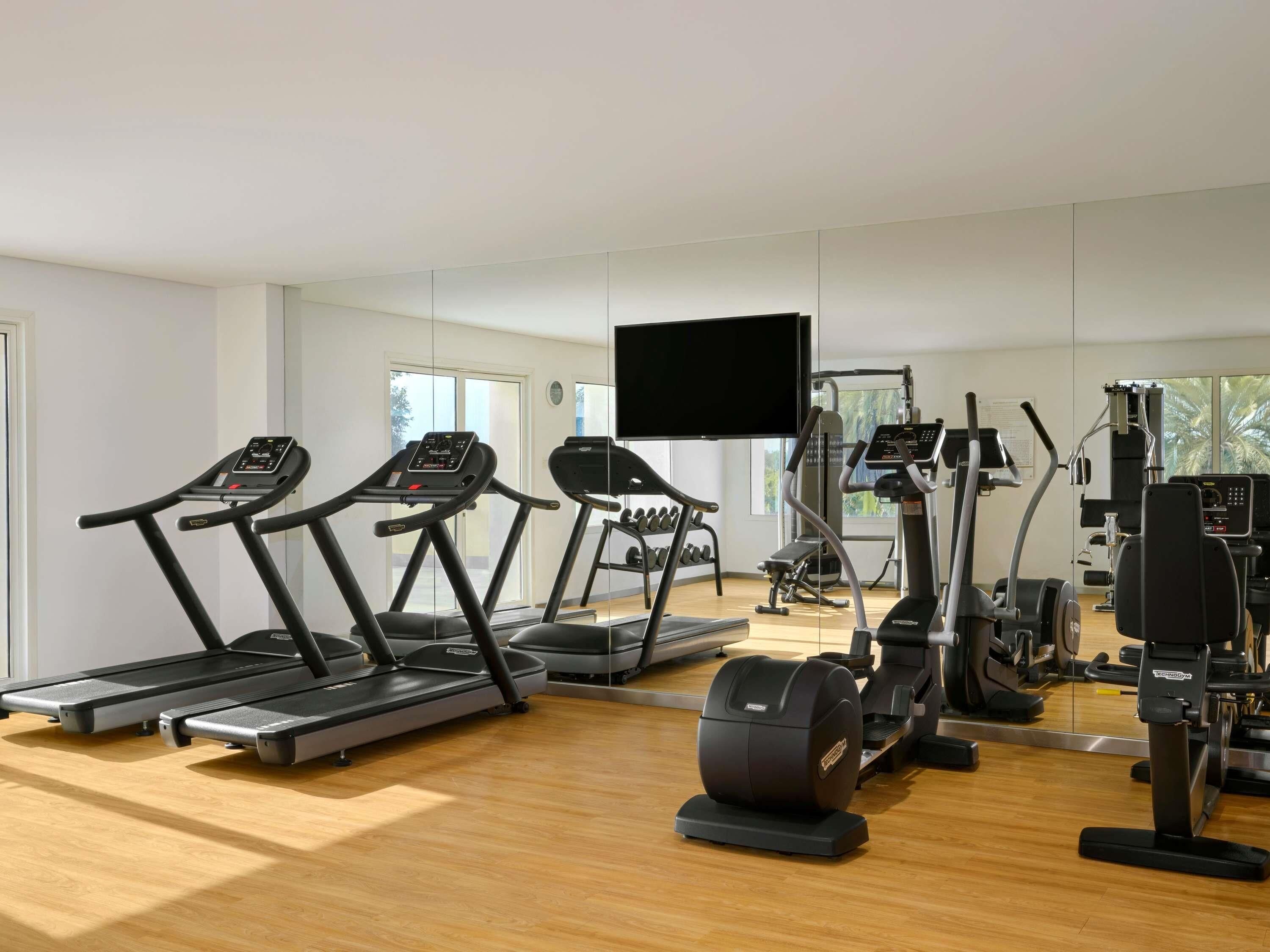 A gym with treadmills, weight machines, and a large mirror.