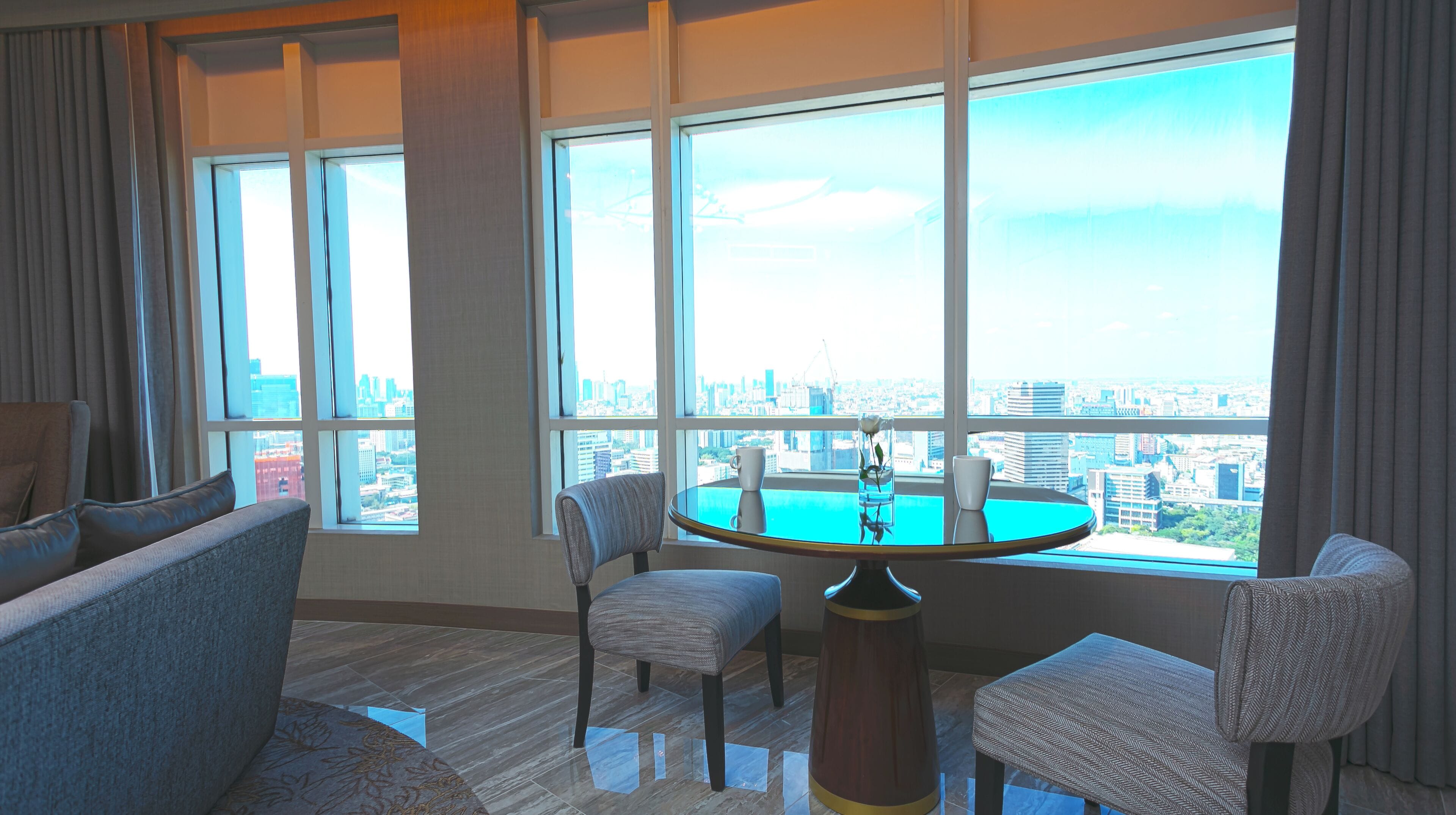 A modern living room with a city view, a round table, and comfortable seating.