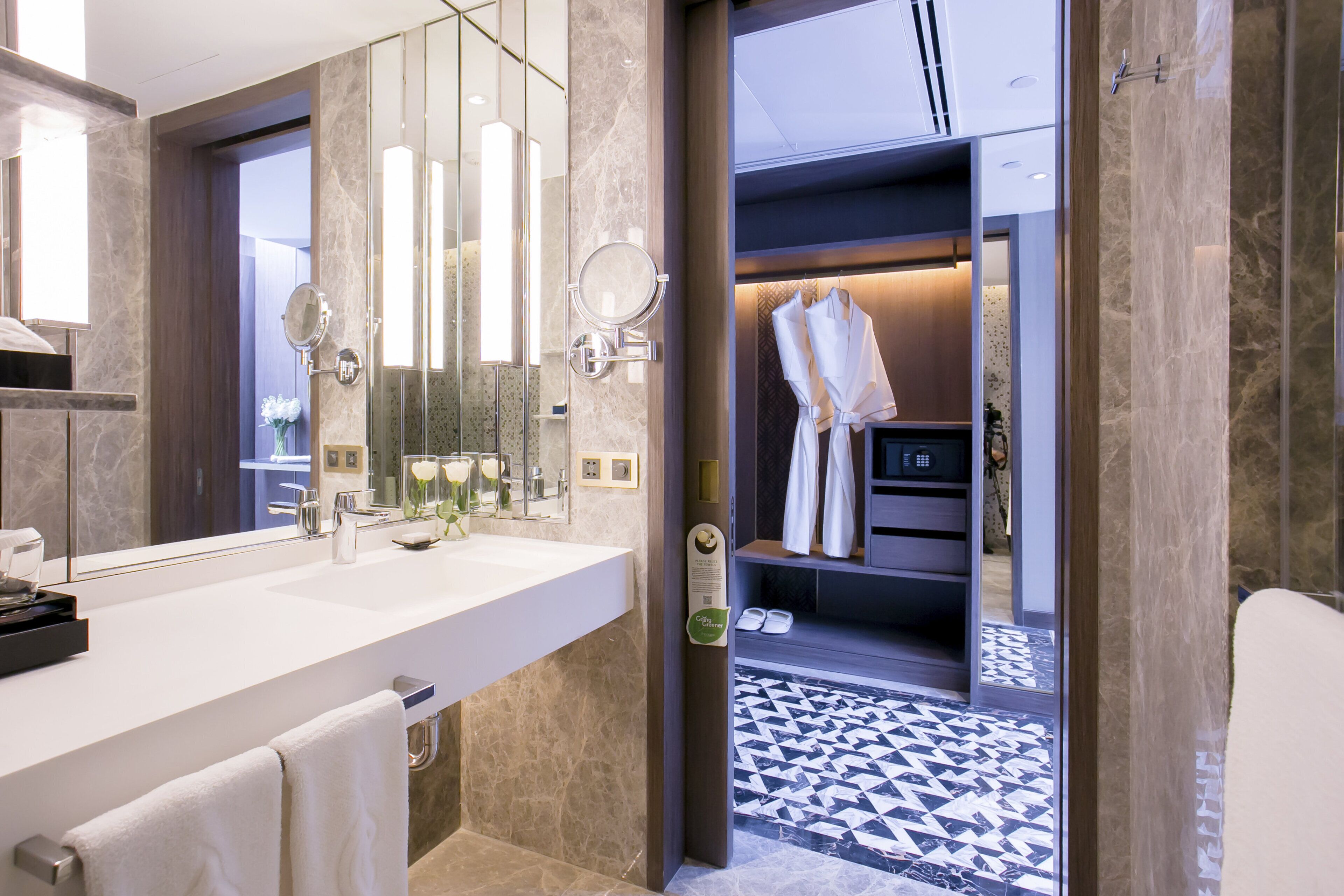 A modern bathroom with a large mirror, a white sink, and a towel rack.