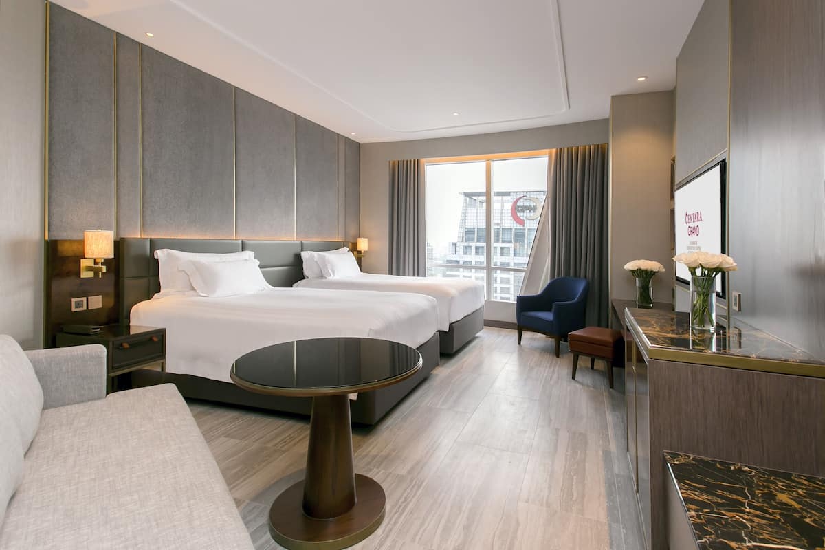 A modern hotel room with a large bed, a desk, and a seating area.