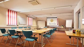 Ein Konferenzraum mit einem langen Tisch, blaugrünen Stühlen, einer Whiteboard-Tafel und einem Präsentationsbildschirm, auf dem das Wort 'Sernia' angezeigt wird.