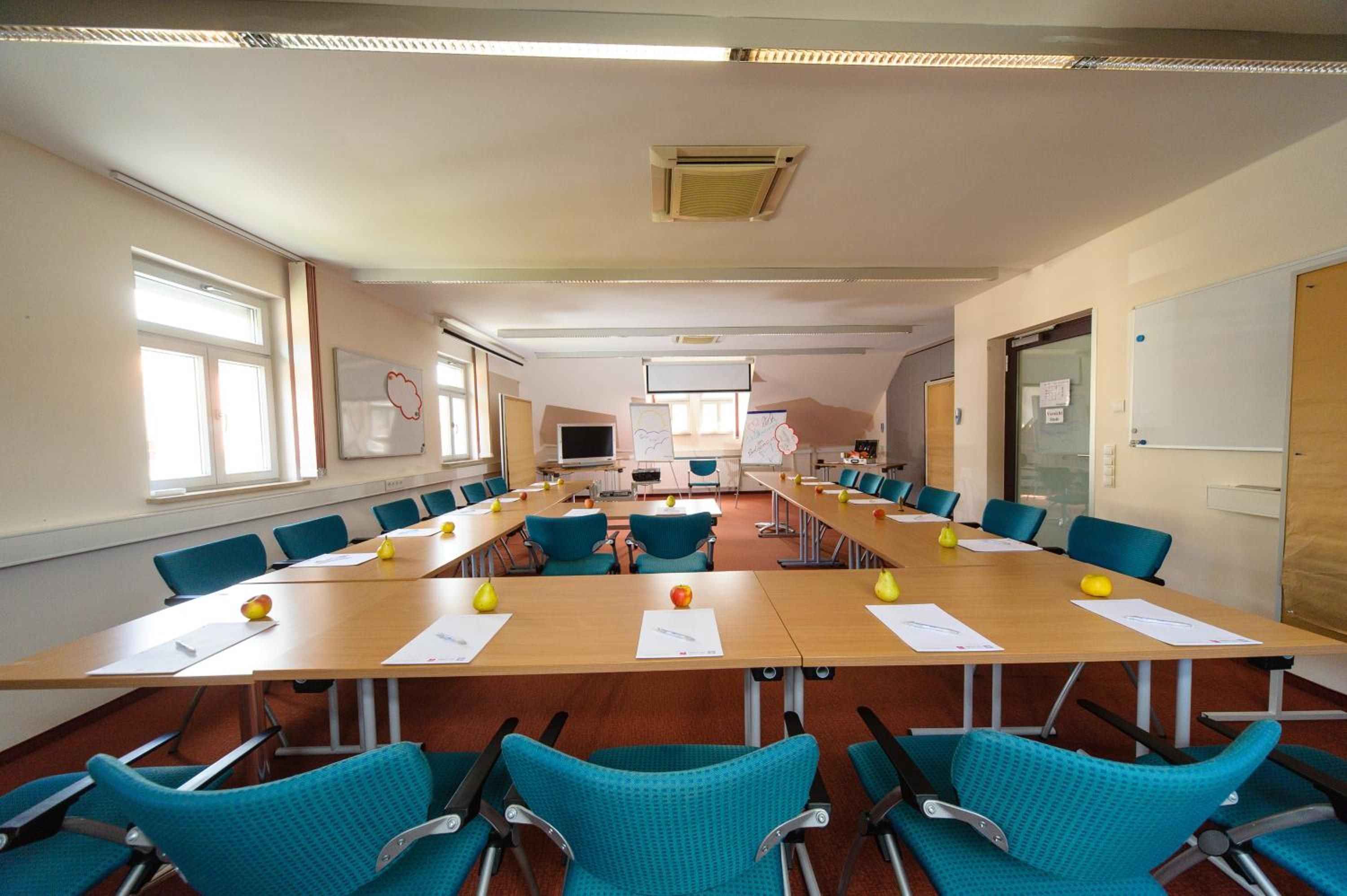 A conference room with long tables, blue chairs, and a whiteboard.