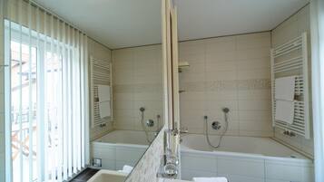 A modern bathroom with two sinks, a bathtub, and a shower.
