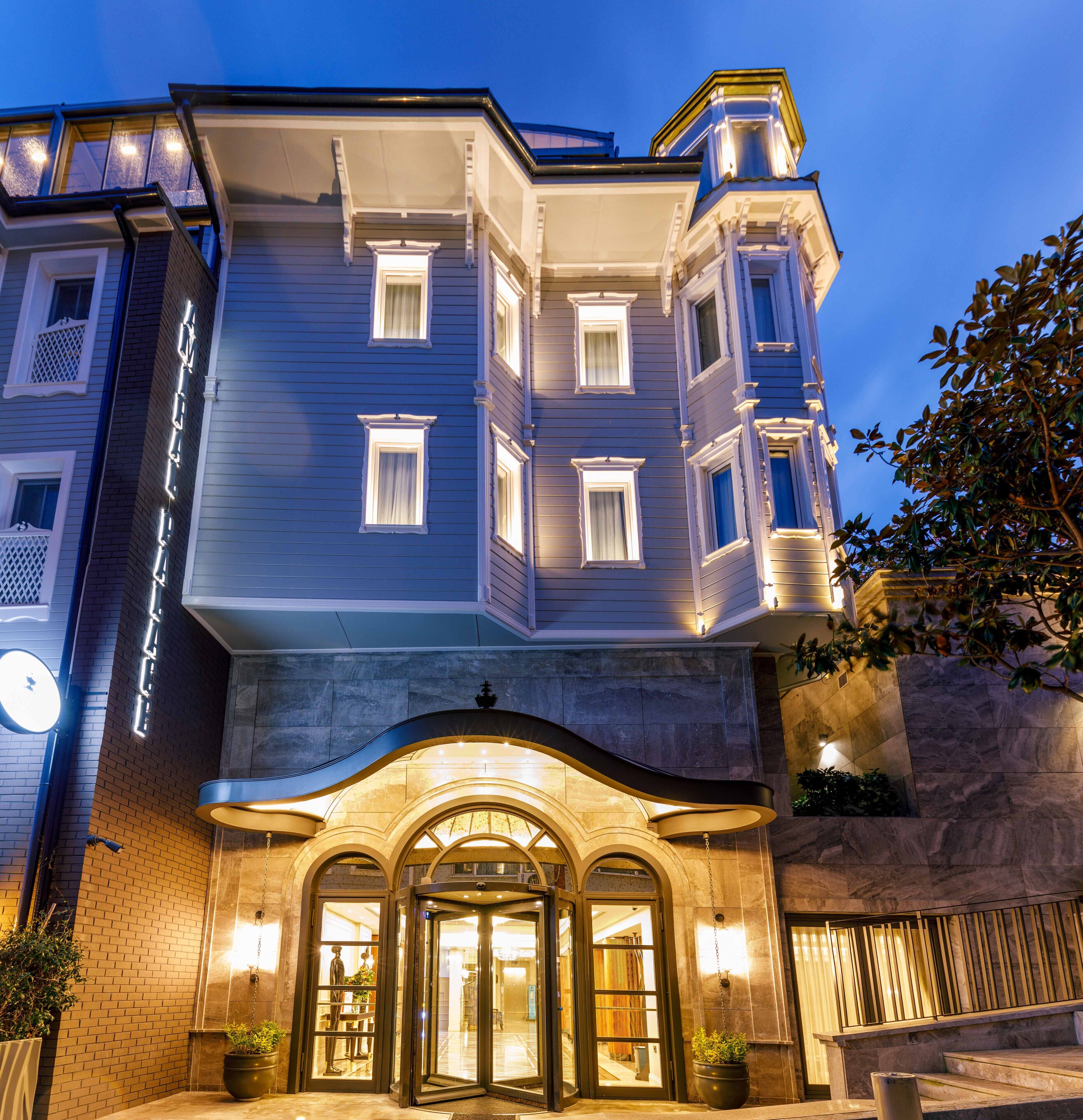 A hotel entrance with a grand archway, multiple windows, and a well-lit facade.