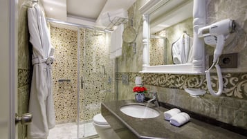 A bathroom with a marble sink, a hairdryer, and a glass shower enclosure.