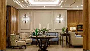 A spacious lobby with a round table, sofas, and a television.