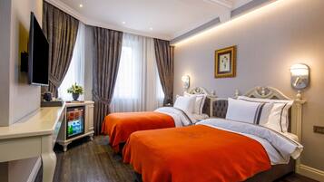 A hotel room with two beds, a television, a minibar, and a picture on the wall.