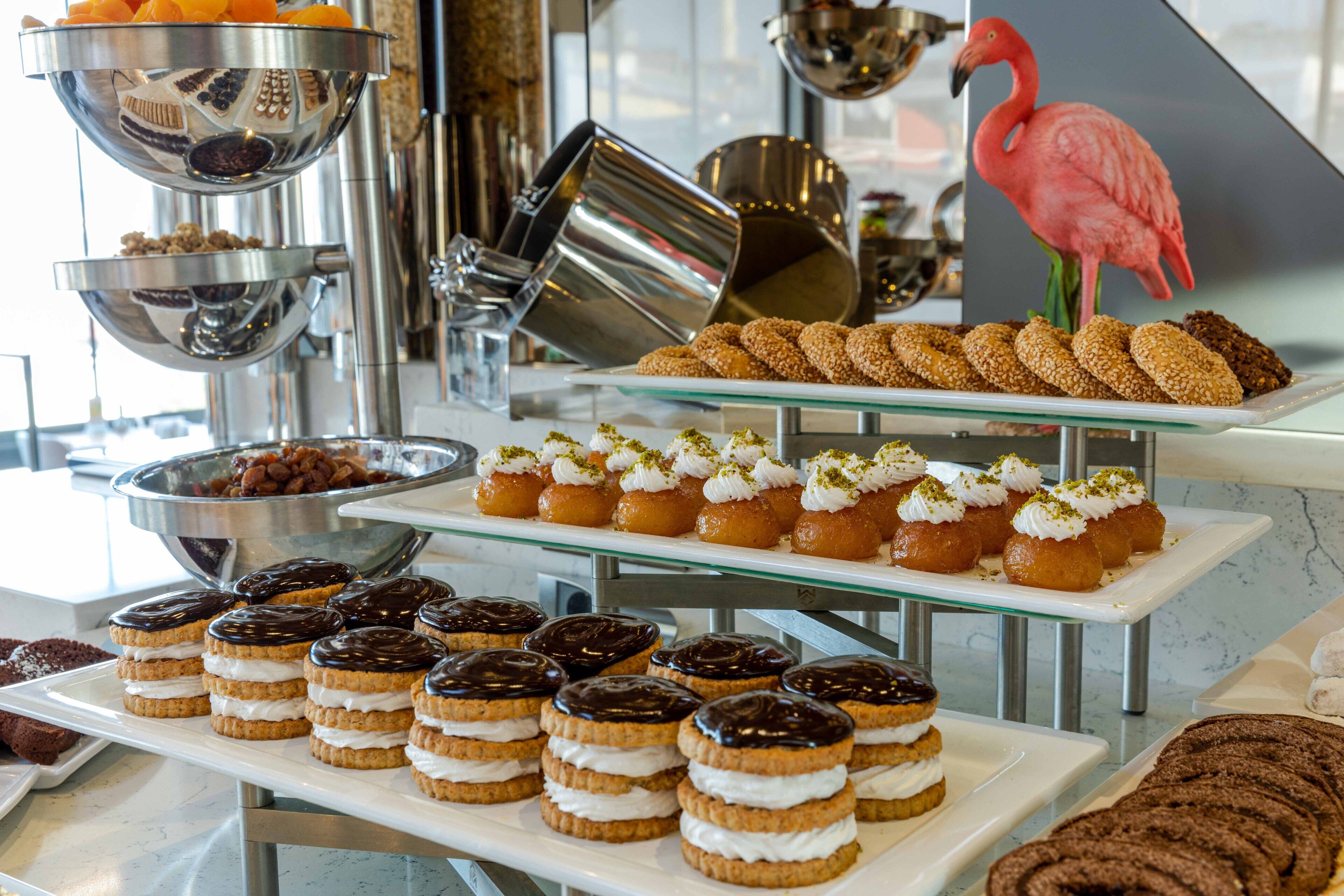A dessert buffet with various pastries and a decorative flamingo.