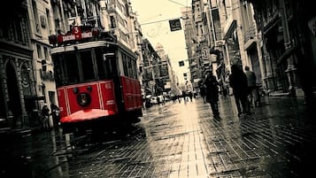 Un tram rouge portant le numéro 410 roule dans une rue de la ville, où le sol est mouillé.
